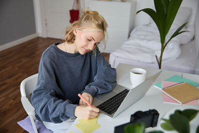 Young woman using laptop while sitting on table