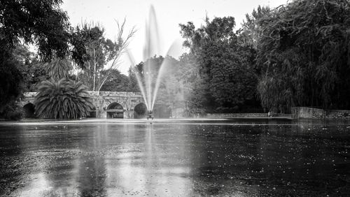 Water fountain in swimming pool against trees