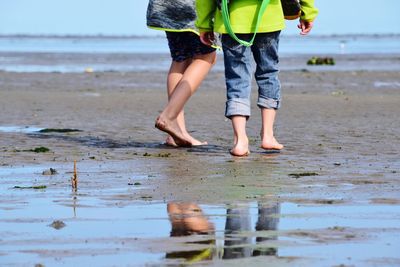 Low section of women standing on beach