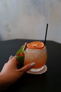 Cropped hand holding drink on table