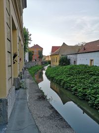 Canal amidst houses and buildings against sky