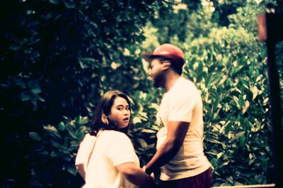 Side view of couple standing against trees