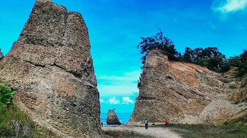 Low angle view of tourists on rock against sky