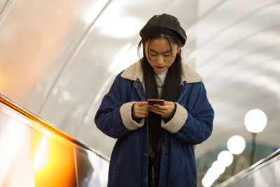 Girl can't live without smartphone. addicted from social media korean female hold phone on escalator