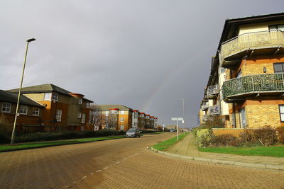 Road by buildings against sky in city