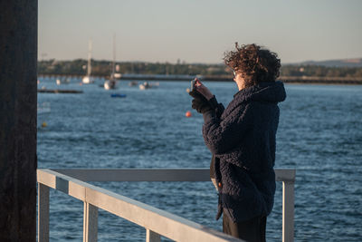 Woman standing by railing against sea
