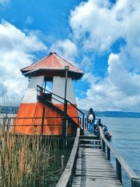 Pier amidst sea by building against sky