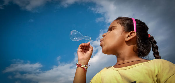 Portrait of woman with bubbles against sky