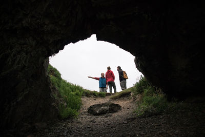 Rear view of people standing on rock against sky