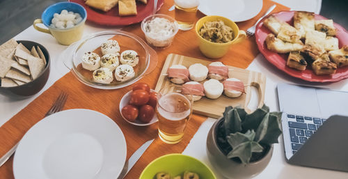 Top view of a table with foods ready for an aperitif. dinner at home, finger food, laptop computer.