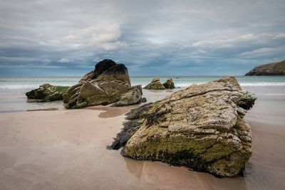 Scenic view of beach against cloudy sky