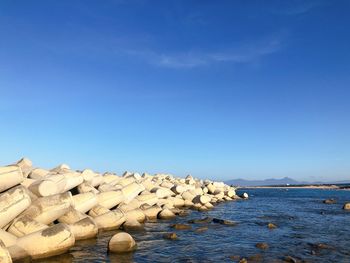 Rocks by sea against blue sky