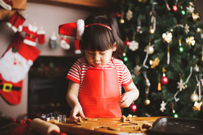 Girl preparing cookies on table during christmas