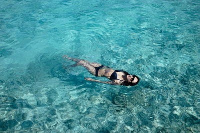 High angle view of woman swimming in a crystal clean ocean 