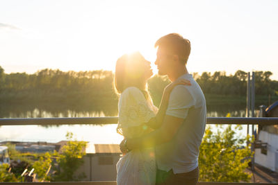 Side view of man and woman standing against sky