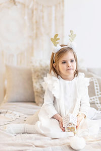 A girl  with a headband  of deer horns and a christmas toy in her hands.christmas holidays