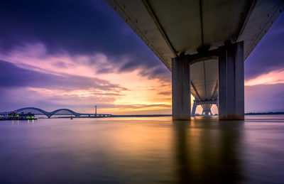 Bridge over river against sky during sunset