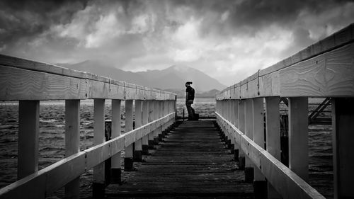 Pier on sea against cloudy sky