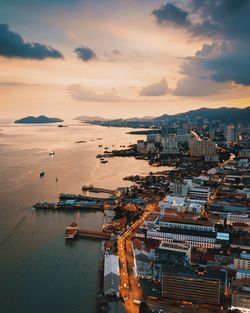 High angle view of cityscape by sea against sky during sunset