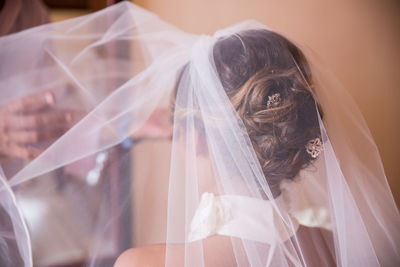 Cropped image of friend putting veil on bride