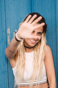 Portrait of young woman gesturing while standing against blue wall