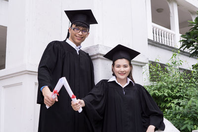 Portrait of smiling students wearing graduation gowns