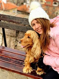 High angle portrait of young woman with dog on bench