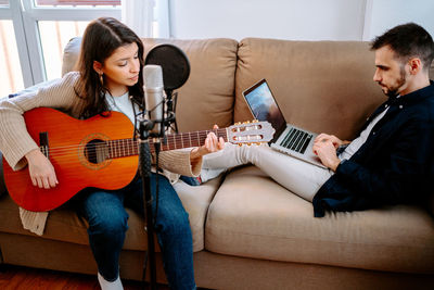 Young man playing guitar on sofa