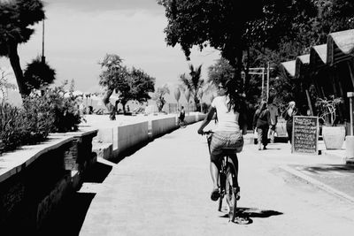 Rear view of woman riding bicycle on road