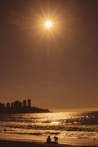 Silhouette of city at seaside during sunset