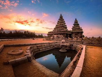 Reflection of temple on building against sky during sunset