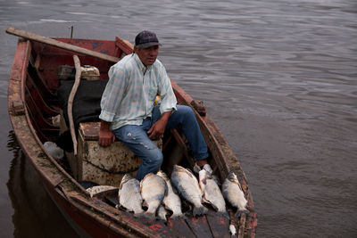 Man sitting in fishing boat on lake