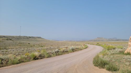 Dirt road amidst landscape against clear sky