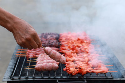 Person holding meat on barbecue grill