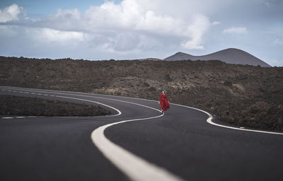 Young woman walking on road at los hervideros, lanzarote, spain