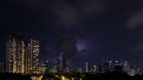 Illuminated buildings in city against sky at night