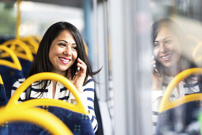 Happy woman talking on smart phone and traveling in bus