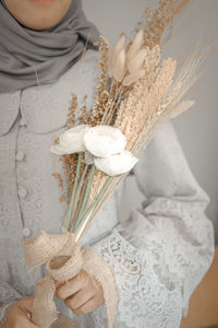 Midsection of woman holding white flowering plant