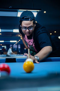 Portrait of young woman playing pool table