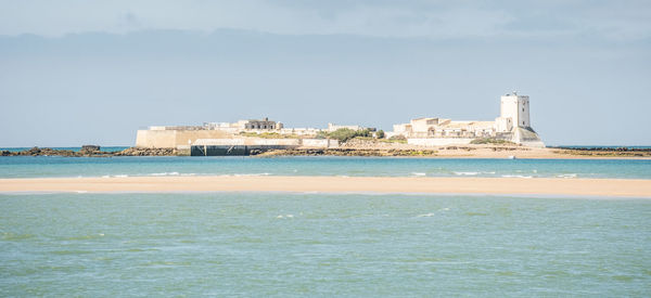 Built structure on beach by sea against sky