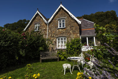 House amidst plants and lawn in front of building