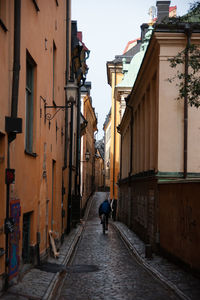 Rear view of man walking on footpath amidst buildings