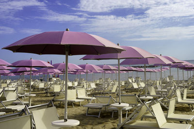 Deck chairs and parasols on beach against sky