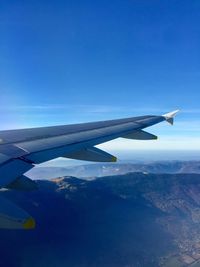 Airplane flying over landscape against blue sky