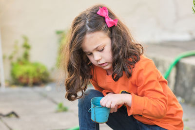 Little girl playing with bucket and plant seeds in the back yard