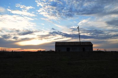 House on field against sky during sunset