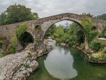 Arch bridge over river against sky