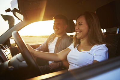 Smiling couple traveling in car seen through window