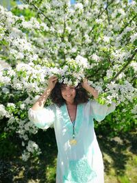 Portrait of mature woman smiling while standing against flowering tree