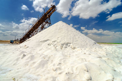 Heap of salt by machinery against blue sky